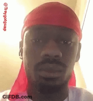 A Man With A Beard And A Red Headband Is Making A Funny Face . GIF