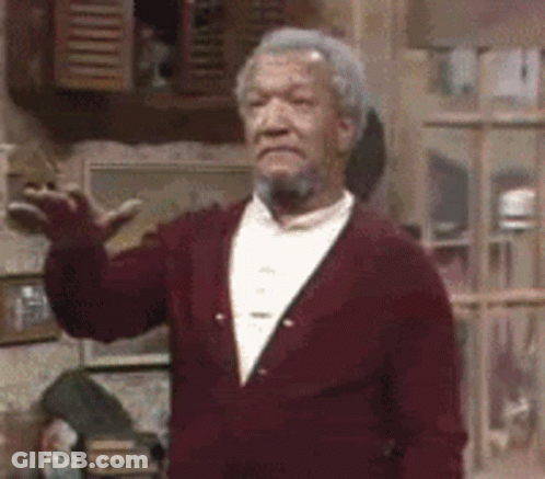 A Man With A Beard And A Red Jacket Is Standing In A Room . GIF