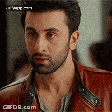 A Man With A Beard And A Red Leather Jacket Is Looking At The Camera . GIF