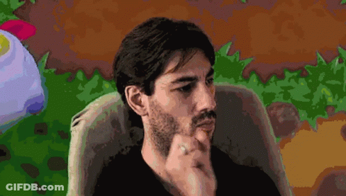 A Man With A Beard And A Ring On His Finger Is Sitting In A Chair GIF