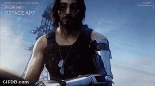 A Man With A Beard And A Robot Arm Is Standing In Front Of A Building . GIF
