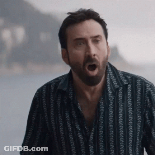 A Man With A Beard And A Striped Shirt Is Making A Funny Face . GIF