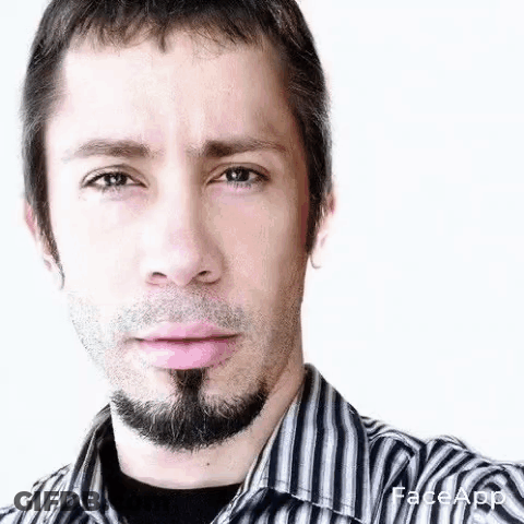 A Man With A Beard And A Striped Shirt Is Making A Funny Face . GIF