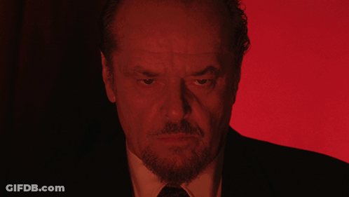 A Man With A Beard And A Suit Is Looking At The Camera With A Red Background GIF