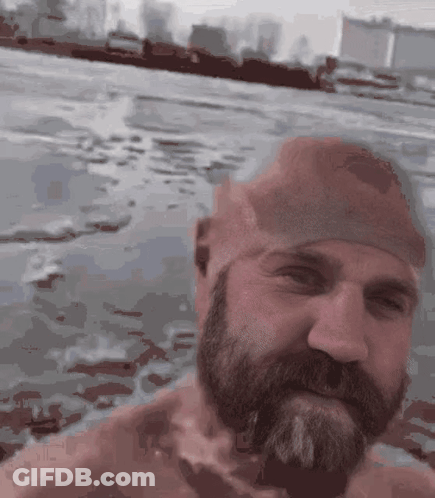A Man With A Beard And A Swim Cap Is Swimming In The Water GIF
