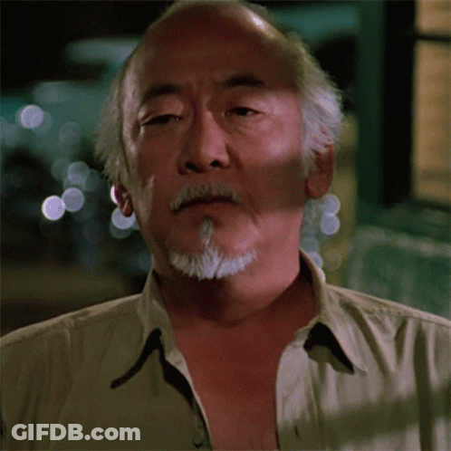 A Man With A Beard And A Tan Shirt Is Looking At The Camera GIF