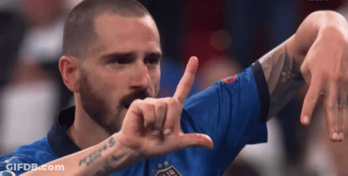 A Man With A Beard And A Tattoo On His Arm Is Making A Funny Face With His Hands . GIF
