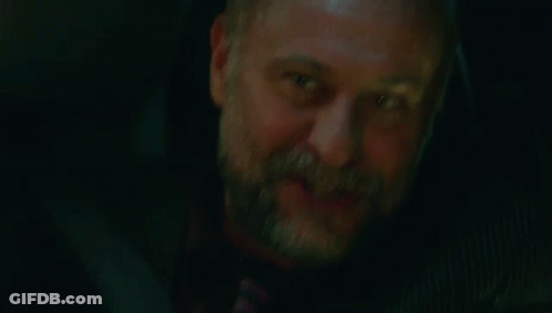 A Man With A Beard And A Tattoo On His Arm Is Smiling And Holding His Hand To His Face . GIF
