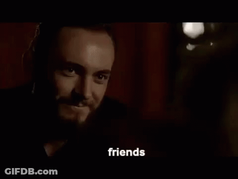 A Man With A Beard And A Tattoo On His Face Is Talking To Someone In A Dark Room . GIF