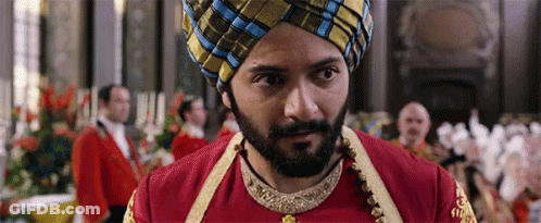 A Man With A Beard And A Turban Is Standing In Front Of A Crowd Of People . GIF