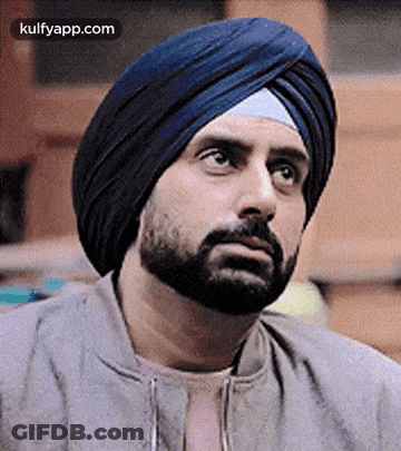 A Man With A Beard And A Turban On His Head Is Looking Up . GIF
