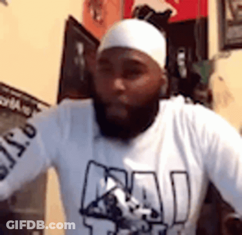 A Man With A Beard And A White Headband Is Wearing A White Shirt . GIF