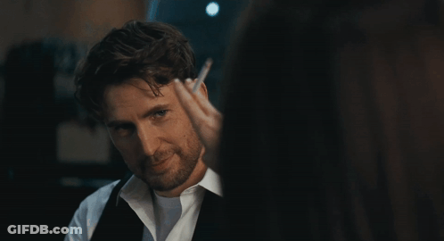 A Man With A Beard And A White Shirt Is Looking At A Woman GIF
