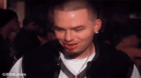 A Man With A Beard And A White Shirt Is Making A Funny Face . GIF