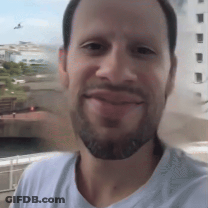 A Man With A Beard And A White Shirt Is Smiling GIF