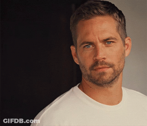 A Man With A Beard And A White Shirt Looks At The Camera GIF