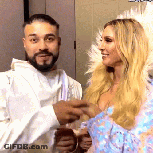 A Man With A Beard And A Woman With Blonde Hair Are Standing Next To Each Other And Smiling .. GIF