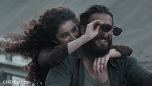 A Man With A Beard And A Woman With Curly Hair On His Back GIF