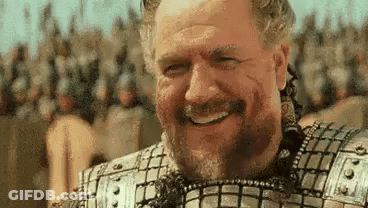 A Man With A Beard And Armor Is Smiling In Front Of A Crowd Of Soldiers . GIF