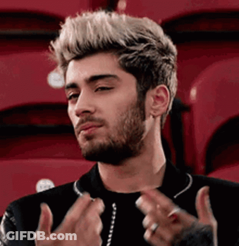 A Man With A Beard And Blonde Hair Is Sitting In A Stadium With Red Seats . GIF