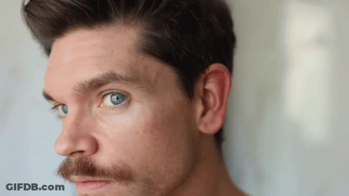 A Man With A Beard And Blue Eyes Is Looking At The Camera GIF