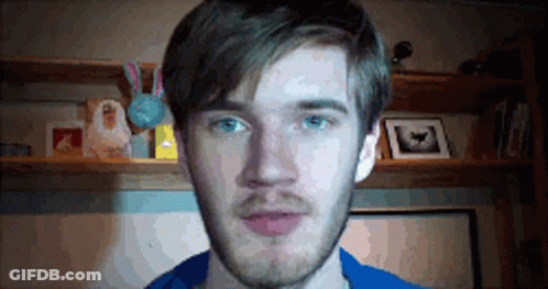 A Man With A Beard And Blue Eyes Is Standing In Front Of A Shelf With Pictures On It . GIF