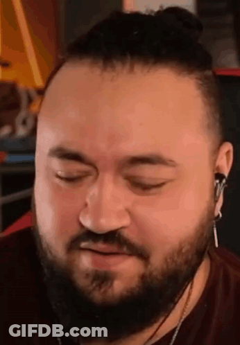 A Man With A Beard And Bun Is Wearing Headphones And Making A Face . GIF