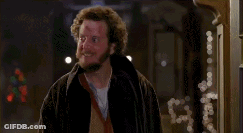 A Man With A Beard And Curly Hair Is Standing In Front Of A Doorway . GIF