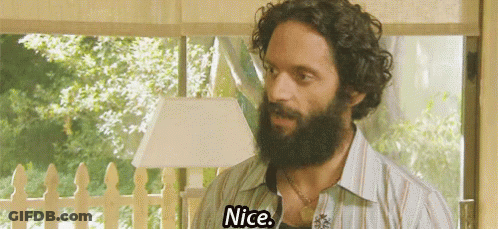 A Man With A Beard And Curly Hair Is Standing In Front Of A Window And Saying Nice . GIF