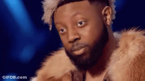 A Man With A Beard And Curly Hair Is Wearing A Fur Coat . GIF