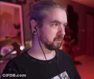 A Man With A Beard And Ear Plugs Is Wearing A Black Shirt . GIF