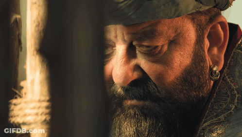 A Man With A Beard And Earring Is Looking Through A Window GIF