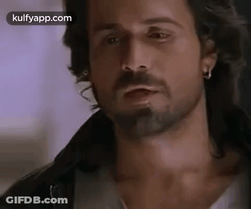 A Man With A Beard And Earrings Is Wearing A Leather Jacket . GIF