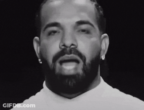 A Man With A Beard And Earrings Looks At The Camera GIF
