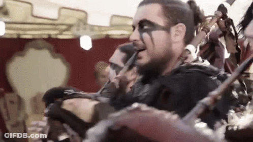 A Man With A Beard And Face Paint Is Playing A Musical Instrument In A Band . GIF