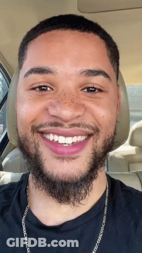 A Man With A Beard And Freckles Is Smiling In The Back Seat Of A Car GIF