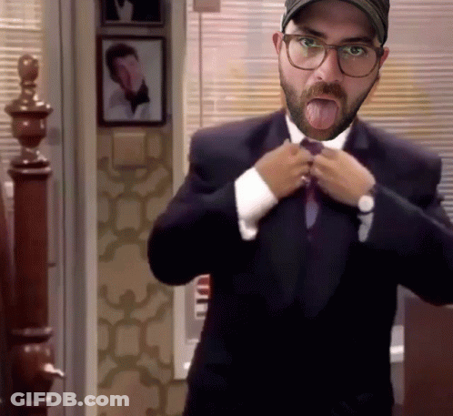 A Man With A Beard And Glasses Is Adjusting His Tie And Sticking His Tongue Out GIF