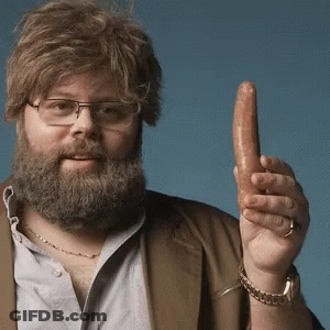 A Man With A Beard And Glasses Is Holding A Sausage In His Hand GIF