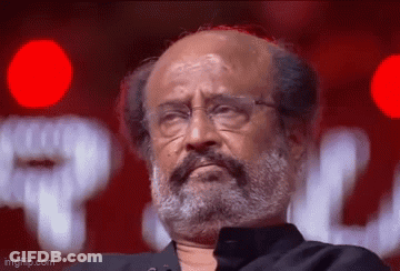 A Man With A Beard And Glasses Is Looking At The Camera . GIF