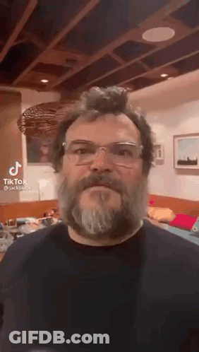 A Man With A Beard And Glasses Is Making A Funny Face . GIF