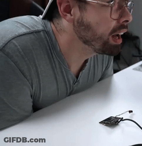 Bearded Man With Glasses Sitting At Table With Device GIF