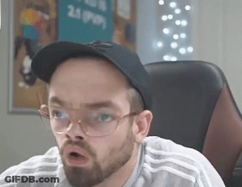 A Man With A Beard And Glasses Is Sitting In A Chair Wearing A Hat And Glasses . GIF