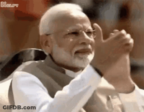 A Man With A Beard And Glasses Is Sitting In A Chair With His Hands In The Air . GIF
