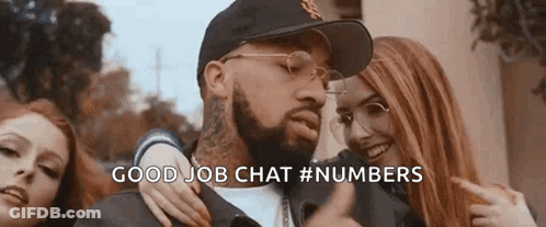 A Man With A Beard And Glasses Is Standing Next To Two Women And Pointing At Them . GIF