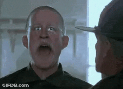 A Man With A Beard And Glasses Is Talking To Another Man In A Military Uniform . GIF