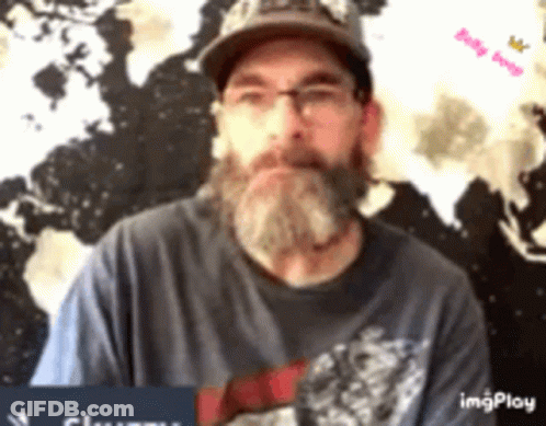 A Man With A Beard And Glasses Is Wearing A Hat And A Blue Shirt . GIF
