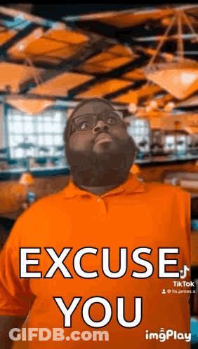 A Man With A Beard And Glasses Is Wearing An Orange Shirt And Making A Funny Face . GIF