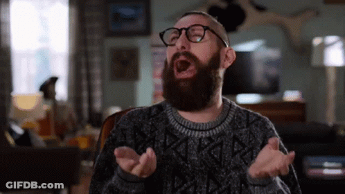 Man With Beard And Glasses Yawning In Living Room GIF