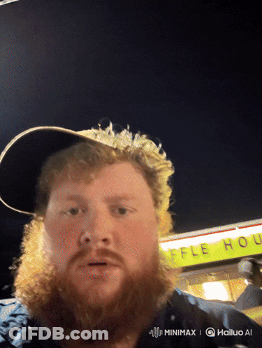 A Man With A Beard And Hat Stands In Front Of A Waffle House GIF