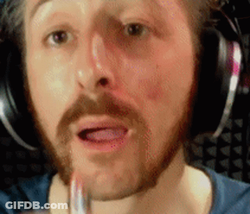 A Man With A Beard And Headphones Is Applying Lipstick To His Lips GIF